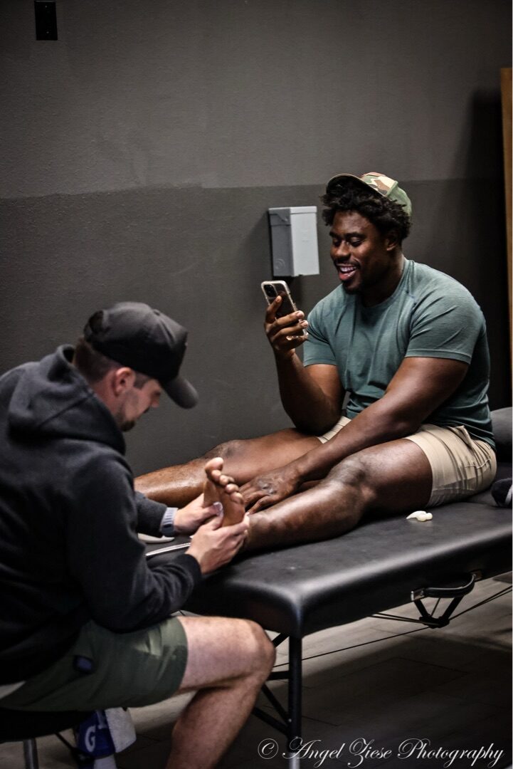 Dr. Tyler Slamans providing hands-on recovery and treatment work on an athlete's foot and lower leg